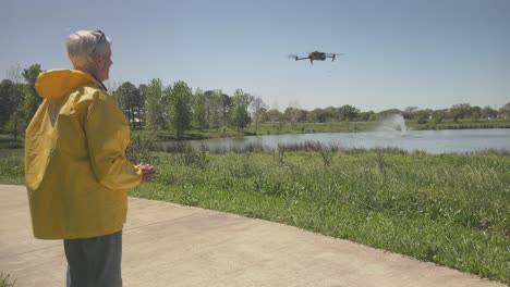 A-senior-male-operates-a-drone,-taking-off-and-flying-over-the-water-at-Exploration-Green-in-Clear-Lake,-Houston,-Texas