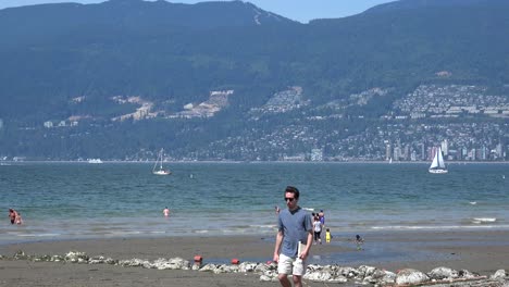 Blick-Auf-West-Vancouver-Mit-Segelboot-Und-Spielenden-Kindern-Am-Strand