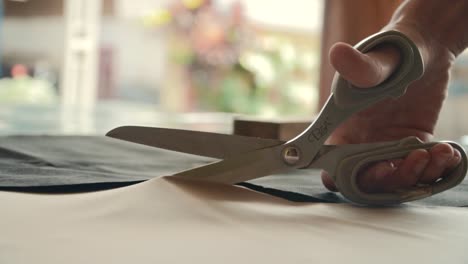 Cut-the-bright-brown-fabric-with-scissors,-close-up