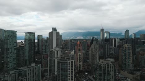 Luftaufnahme-über-Vancouver-City-Mit-Blick-Auf-Die-Skyline-Und-Die-Berge-Dahinter-An-Einem-Bewölkten-Tag,-British-Columbia,-Kanada