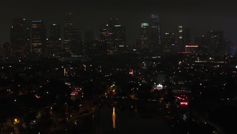 Downtown-Los-Angeles-overlooking-Echo-Park-on-misty-night,-aerial-drone-rising-of-city