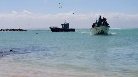 Fishermen-aboard-an-open-boat-enter-a-natural-harbor-on-the-South-coast-of-South-Africa