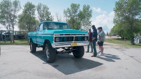 A-Group-of-Young-Men-Stand-and-Admire-a-Lifted-Vintage-Pickup-Truck-at-an-Outdoor-Car-Show