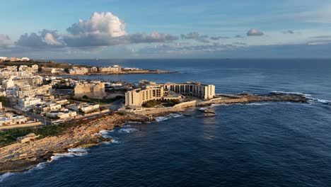 Aerial-view-of-l-Jerma-Bay-and-Abandoned-Jerma-Palace-Hotel-in-Marsaskala,-sunrise-time,-Malta