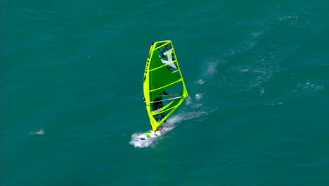 Flying-overhead-a-windsurfer,-pulling-out-to-a-wide-shot-as-he-races-towards-the-beach