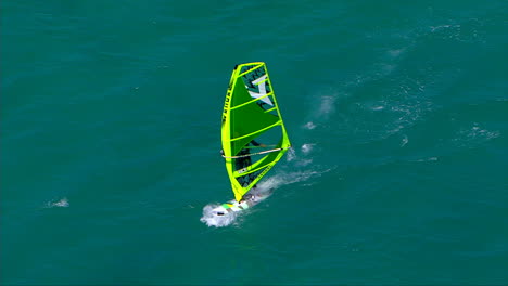 Fliegt-über-Einen-Windsurfer-Hinweg-Und-Zieht-Sich-Zu-Einer-Totalen-Zurück,-Während-Er-Auf-Den-Strand-Zurast