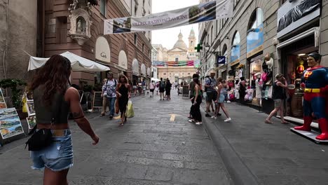 Handheld-Clip-Zu-Fuß-Entlang-Einer-Belebten-Gepflasterten-Straße-Gesäumt-Mit-Geschäften-Und-Restaurants-In-Italien