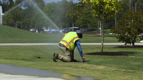 Trabajador-De-Servicios-Públicos-Del-Parque-Público-Haciendo-Ajustes-Al-Rociador-De-Agua-Durante-El-Verano