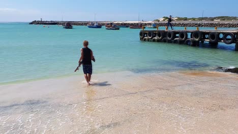 A-teenage-boy-returns-a-small-shark-pup-down-the-slipway-and-back-to-the-ocean