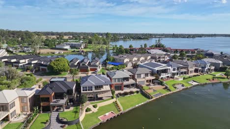 Cruce-Aéreo-Sobre-Casas-Turísticas-Y-Hacia-La-Laguna-Más-Allá-En-Nueva-Gales-Del-Sur,-Australia