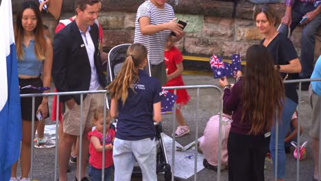 Young-volunteers-giving-away-Australian-national-flag-to-the-people-on-the-street-of-Brisbane-city-on-Anzac-day-before-the-commencement-of-the-parade,-handheld-motion-shot