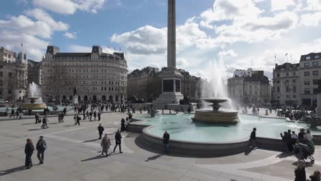 Trafalgar-Square-in-London-bustles-with-pedestrians-strolling-near-the-iconic-water-fountain,-epitomizing-the-vibrant-energy-and-urban-life-of-the-city