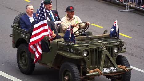 Post-World-War-II-allied-veterans-riding-on-the-military-vehicle,-participating-the-annual-Anzac-Day-parade,-waving-at-the-cheering-crowds,-close-up-shot