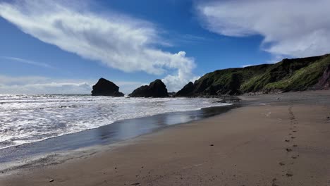 Footprints-in-the-sand-incoming-tide-and-beautiful-clouds-Ballydwane-beach-Copper-Coast-in-Waterford-Ireland-on-a-spring-day