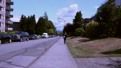 Dolly-shot-on-sidewalk,-walking-behind-a-woman-who-stops