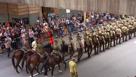 En-La-Solemnidad-Del-Día-De-Anzac,-Las-Tropas-Del-Ejército-Australiano-Marchan-Por-La-Calle,-Algunas-A-Caballo,-Participando-En-La-Tradición-Del-Desfile-Anual-Con-Multitudes-Aclamando-A-Lo-Largo-De-La-Calle.