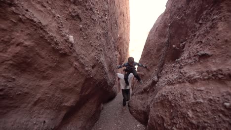 Two-Moroccan-kids-runing-narrow-slot-canyon---gorge-Dades