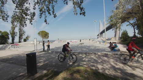 People-skating-and-cycling-in-skatepark-in-a-public-park-in-Parque-das-Nações,-Lisbon,-Portugal