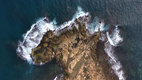 Top-Down-drone-View-Over-A-Rocky-Shore-Line-with-salt-pans-and-Waves-Splashing