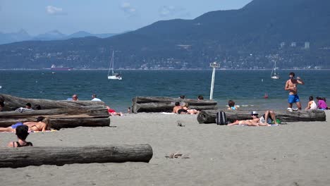 Sonnenanbeter-An-Einem-Ozeanstrand-Mit-Bergen-Im-Hintergrund