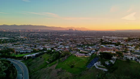 Aerial-drone-viewpoint-cityscape-of-Los-Angeles-LA-Kenneth-Hanh-sightseeing-city-town-with-mountain-background-and-colorful-golden-hour-skyline
