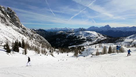 Gente-Esquiando-En-La-Estación-De-Esquí-De-Nassfeld-Con-Los-Nevados-Alpes-Austriacos-Al-Fondo-Durante-El-Invierno