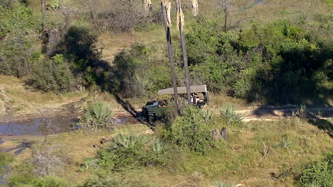 Driving-tourists-along-the-swamps-of-the-Okavango-Delta-in-Botswana,-zooming-out-to-a-wide-shot-of-the-delta