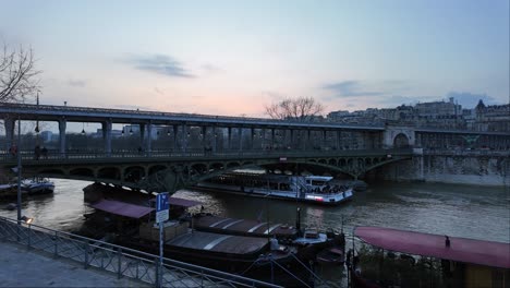 Boat-passing-under-Bir-Hakeim-bridge-crossing-Seine-river,-Paris-at-sunset,-France