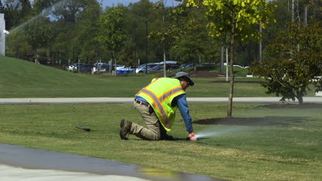 Trabajador-De-Servicios-Públicos-Del-Parque-Público-Comprobando-La-Funcionalidad-Del-Rociador-De-Agua-Subterránea-En-Una-Calurosa-Tarde-De-Verano