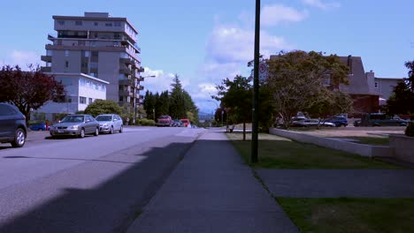 Forward-dolly-shot-on-sidewalk-in-residential-area-on-sunny-day