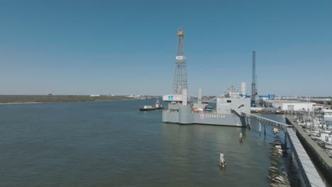 An-aerial-view-zooms-out-of-the-Ocean-Star-Offshore-Drilling-Rig-and-Museum-under-clear-blue-skies-in-the-Galveston-Channel,-Galveston,-Texas