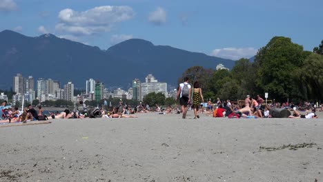 A-couple-walk-together-on-a-beach-with-sunbathers