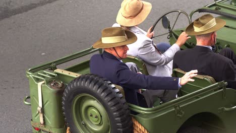 Senior-veterans-riding-on-the-vintage-military-vehicle,-driving-down-the-street,-participating-the-annual-Anzac-Day-parade-tradition,-close-up-shot