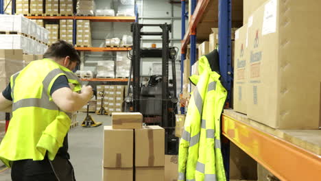 Man-in-warehouse-putting-on-hi-vis-safety-vest,-shelves-with-boxes-in-background,-indoor-lighting