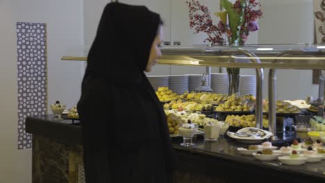 Woman-Wearing-All-Black-Walking-And-Looking-At-Delicious-Desserts-In-Restaurant