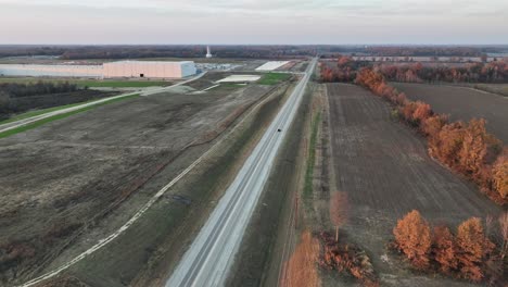 Aerial-following-vehicle-driving-alongside-Ford's-Megacampus,-BlueOval-City-at-Sunset-in-Stanton,-TN