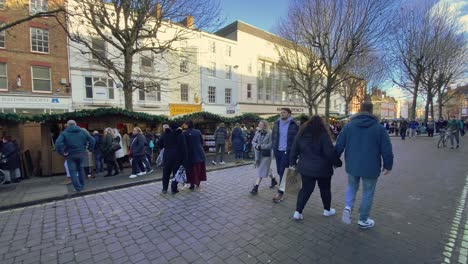 A-busy-city-centre-street-comes-alive-with-holiday-spirit-as-pedestrians-bustle-by-adorned-shops-and-Christmas-festive-decorations-under-a-clear-blue-sky