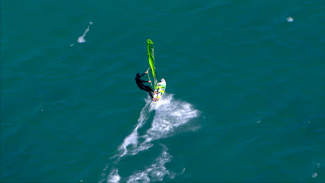 Flying-overhead-a-windsurfer-racing-across-a-flat-ocean