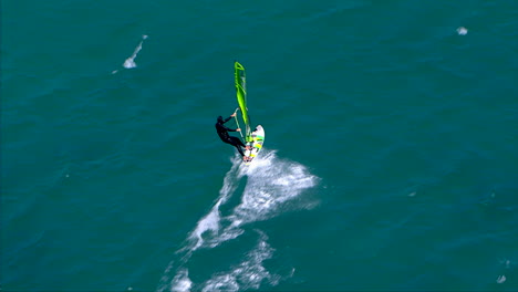 Volando-Sobre-Un-Windsurfista-Corriendo-A-Través-De-Un-Océano-Plano