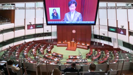 Carrie-Lam,-former-Hong-Kong-chief-executive,-is-seen-on-a-screen-as-she-delivers-her-annual-policy-address-at-the-Legislative-Council-Chamber-in-Hong-Kong