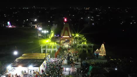 Vista-Aérea-De-Drones-Cámara-De-Drones-Avanzando-Donde-Muchas-Personas-Observan-El-Espectáculo-De-Luces-Del-Shivling-De-Mahadev