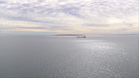 Buque-De-Carga-Saliendo-De-Table-Bay,-Con-La-Isla-Robben-Al-Fondo