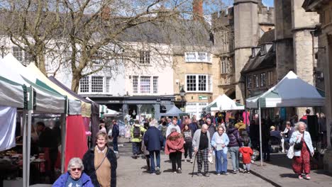 Crowds-of-people-shopping-at-fruit,-vegetable,-food,-arts-and-crafts-stalls-at-Wells-Market-Place-over-busy-Easter-Weekend-in-historic-city,-Southwest-of-England-UK