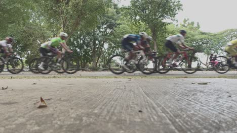 Low-angle-ground-surface-pov-of-professional-cyclists-cycling-during-cycling-race-in-Mirador-Sur-Park-of-Dominican-Republic
