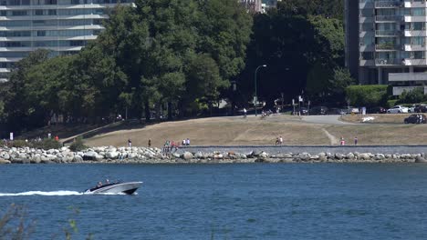 Speedboat-moving-at-Vancouver-beach-with-bus-moving-in-background