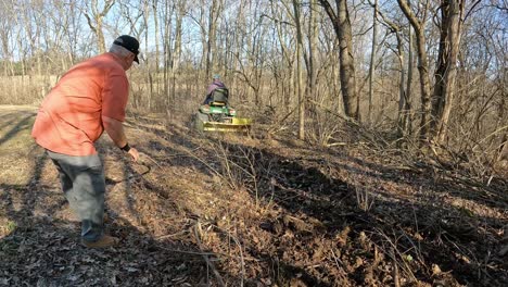 Man-removing-stick-and-other-debris-from-path-of-rototiller