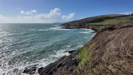 Escarpada-Costa-De-Irlanda-En-Un-Día-Soleado-De-Mayo-Con-Olas-Y-Campos-Verdes,-Amplio-Panorama