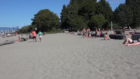 Zwei-Spaziergänger-An-Einem-Strand-Mit-Sonnenanbetern-Im-Hintergrund