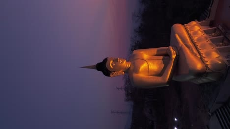 Golden-Buddha-overlooking-Mekong-river-vibrant-sunset,-Pakse,-Laos