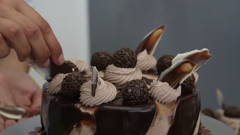 Indulge-in-chocolate-temptation:-close-up-shot-captures-a-chocolate-cake-being-decorated-with-delightful-chocolate-adornments